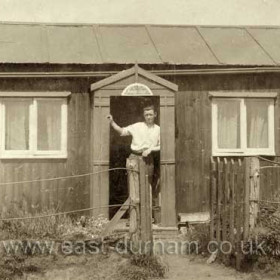 Joe Parkin at his hut doorway in 1933, the address was 53 Blue House Crimdon.
This is one of the huts that were in Crimdon Dene in the early 30s the notice on the side of the hut tells you when the well water was available.
Photograph and caption from Bob Williams