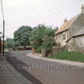 Looking west in Dalton le Dale ( church behind the red car ). The tall building on the right is the old vicarage, probably built in 1370 with the upper storey being reached by an outside staircase. In 1670 the vicar at the time, Thomas Sharpe partially rebuilt the vicarage, adding the west end and placing a stone above the door bearing his name and the date. Purchased in the late 1950's by Frank Thubron it was demolished in Sept 1962, not because of it's condition but to facilitate entry to garages on their land.Mr C and Mrs C Middlemiss were the last to occupy the house in the 1950s