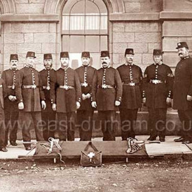 Seaham Police outside a relatively new looking Tempest Road Police Station. I have been unable to date the uniform but the shaka cap was introduced about 1860, this along with the new looking building (built 1861) and pavement suggest a date between 1865 and 1885. 
Not sure why the stretcher is there but it could have been used to get the numerous miscreants back to the station after being whacked over the head with a truncheon.