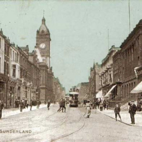 A postcard dated 2nd January 1905.
An interesting picture of Fawcett Street at the beginning of the 20th century. Two open top tramcars are seen travelling along the newly electrified tramway. Vincent's Music Rooms are on the immediate left.
Behind the policeman and next to the post box is the points boy's box. He can be seen standing on the kerbside in the process of pulling the lever which will alter the junction on the overhead wire. With the rod in his left hand he will go and change the points on the track crossover to allow the tram to proceed on either the Durham Road route or the Christ Church route. The track on the right took trams onto the Villette Road route which at this time was operated only by single deck trams because of a low bridge in Tatham Street. To the right of the tram is the tower platform used in the maintainance and repair of the overhead wires.