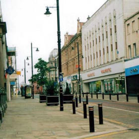 2002. Even the zebra crossing is now redundant. Whilst the bollards and plant tubs may be considered to be an attribute, lending some sort of fake charm to the street scene, I suspect their presence is intended for a completely different purpose, and that is to prevent car borne thieves from smashing into the shop fronts in order to gain illegal access.