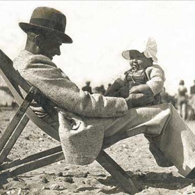 ROKER BEACH IN AUGUST 1936
This pleasant scene on Roker beach is not what it seems. Sunderland was suffering during the awful economic depression of the 1930's. The town was famous for shipbuilding but all the yards were closed, thousands of men were unemployed, and the beach was one of the few free attractions. When Mam was in labour delivering me in August 1935, my Dad spent his last penny on an ice-cream for her and, after my arrival, she was granted one shilling (5p) a week to feed me. I do look amazingly plump sitting on Dad's knee, I think I was brought up on cocoa, porridge and broth.
Photograph & caption, Malcolm Fraser