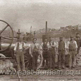 Workmen at Seaham Dock. Steam engine? at left, equipment at right looks like some sort of surveying gear. Possibly blockyard in background. Date not known.