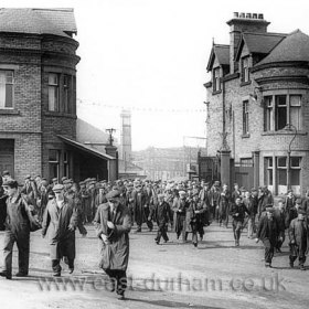 It is ‘knocking-off time’ at William Doxford & Sons shipyard as the gates are opened and the workmen flood out, hurrying for the buses. Those turning towards the left are going to Ford Estate or Humbledon, or maybe just going as far as Pallion. The lads coming towards us will be going over the Queen Alexandra bridge to Southwick, Marley Potts or further afield. Its probably the early fifties so they’ll all be earning about five or six pounds a week but Doxfords is a good steady job and its going to be there for ever …..    
Caption from Malcolm Fraser