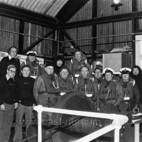 Inside the lifeboat-house in the 1970s
Back Row/ Peter Shaw, Ray Riddell (2nd Coxwain) Steve Riddell, Ronnie Leng.
Front Row/ Vince Price, Jimmy Cougle, Billy Black, John Foreman, Meyburn Murley, Maurice Thornton, Don Cave (Coxwain), Dave Wallace (Mechanic), Fred Wallace, Frank Lane
Photograph by Ian Dobson
Info from Steve Riddell